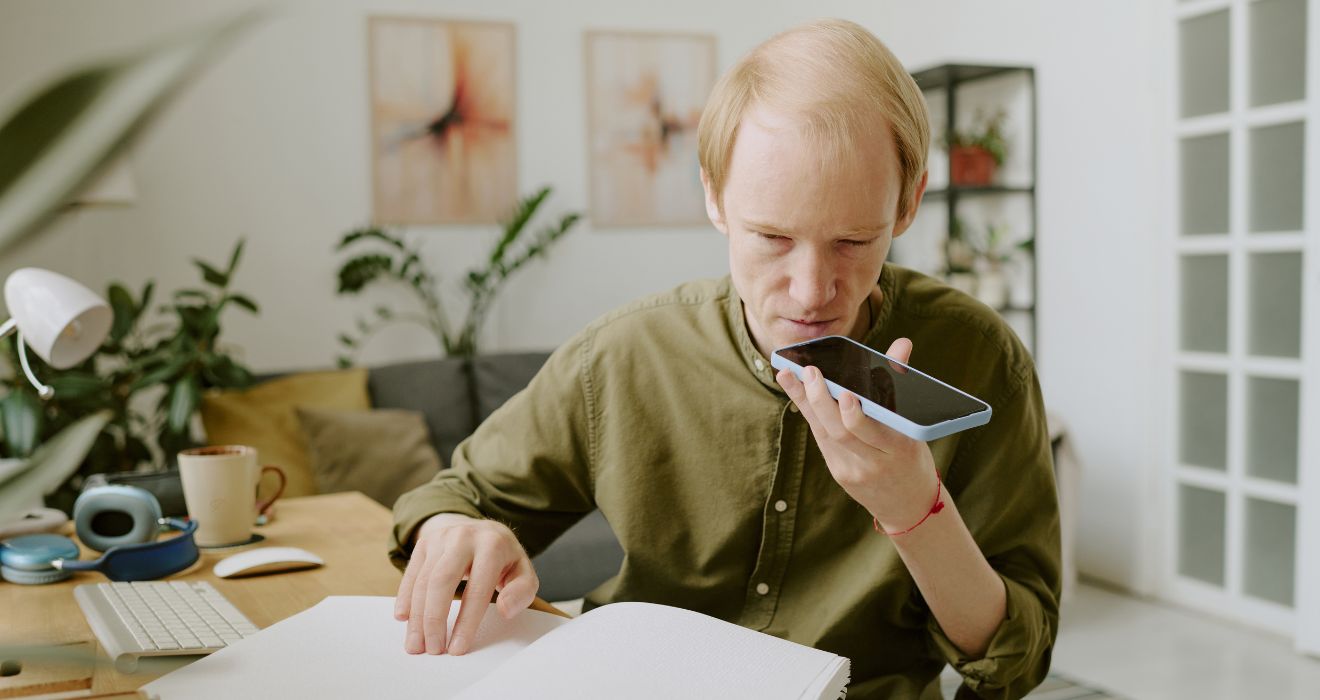 Mężczyzna korzystający z funkcji głosowej w smartfonie – ilustracja dostępności cyfrowej zgodnej z wytycznymi WCAG